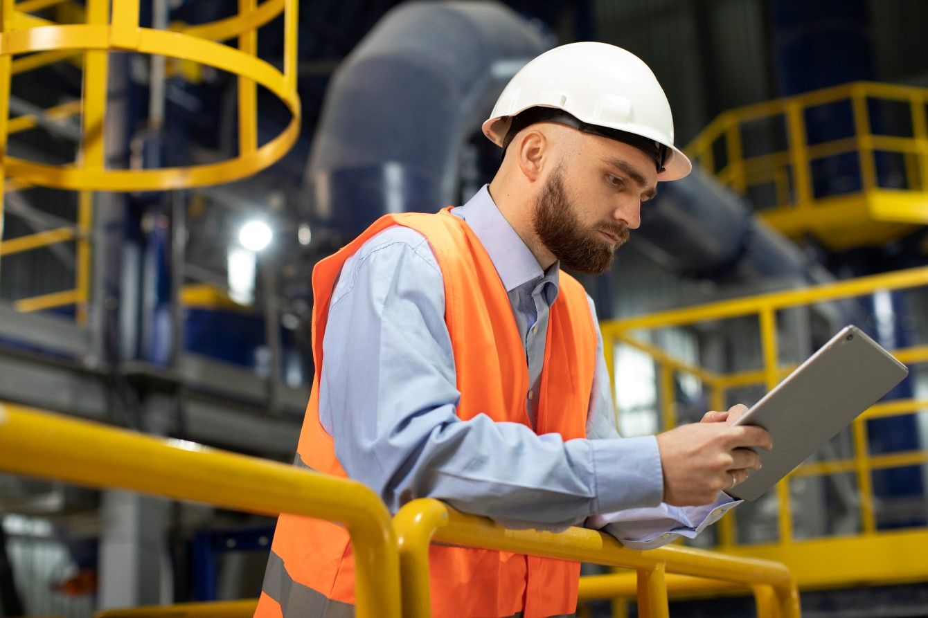 Man met helm houdt tablet vast in productie