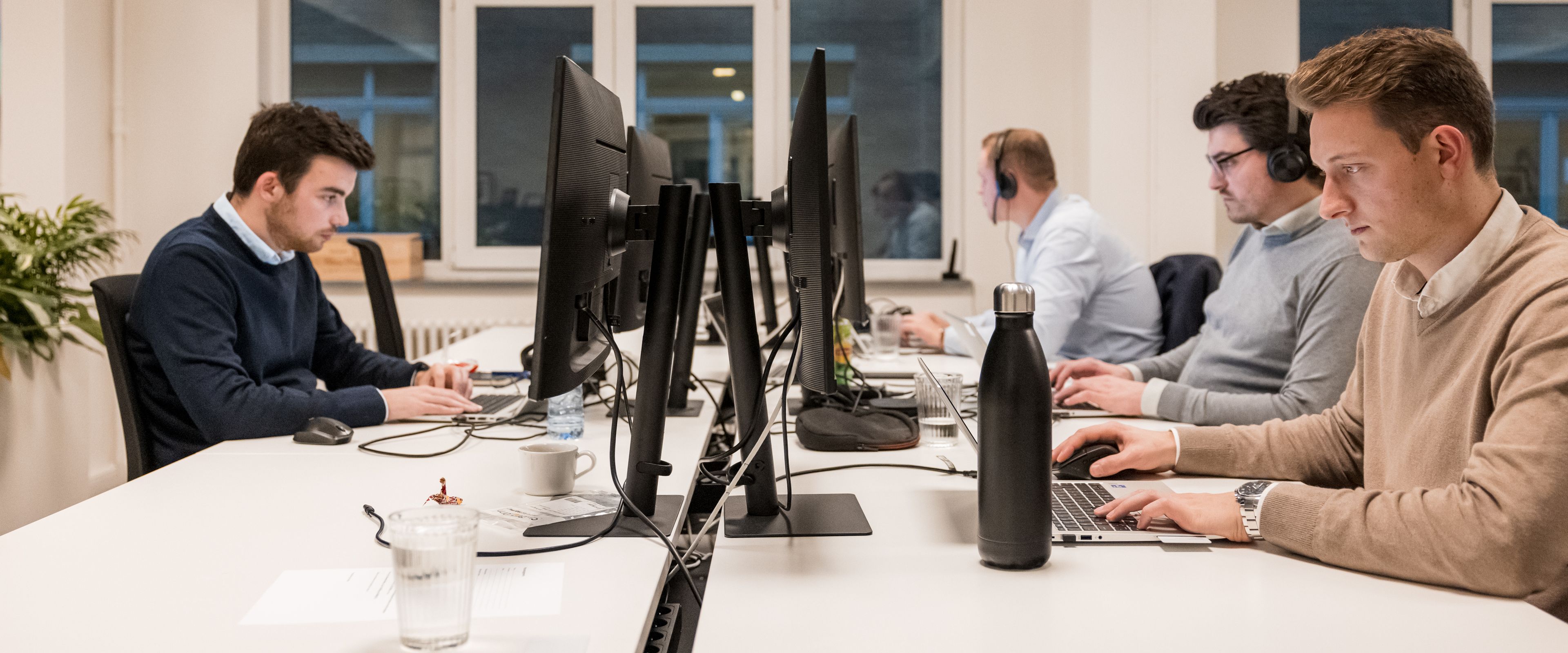 Employees working on computers at shared desks in an office