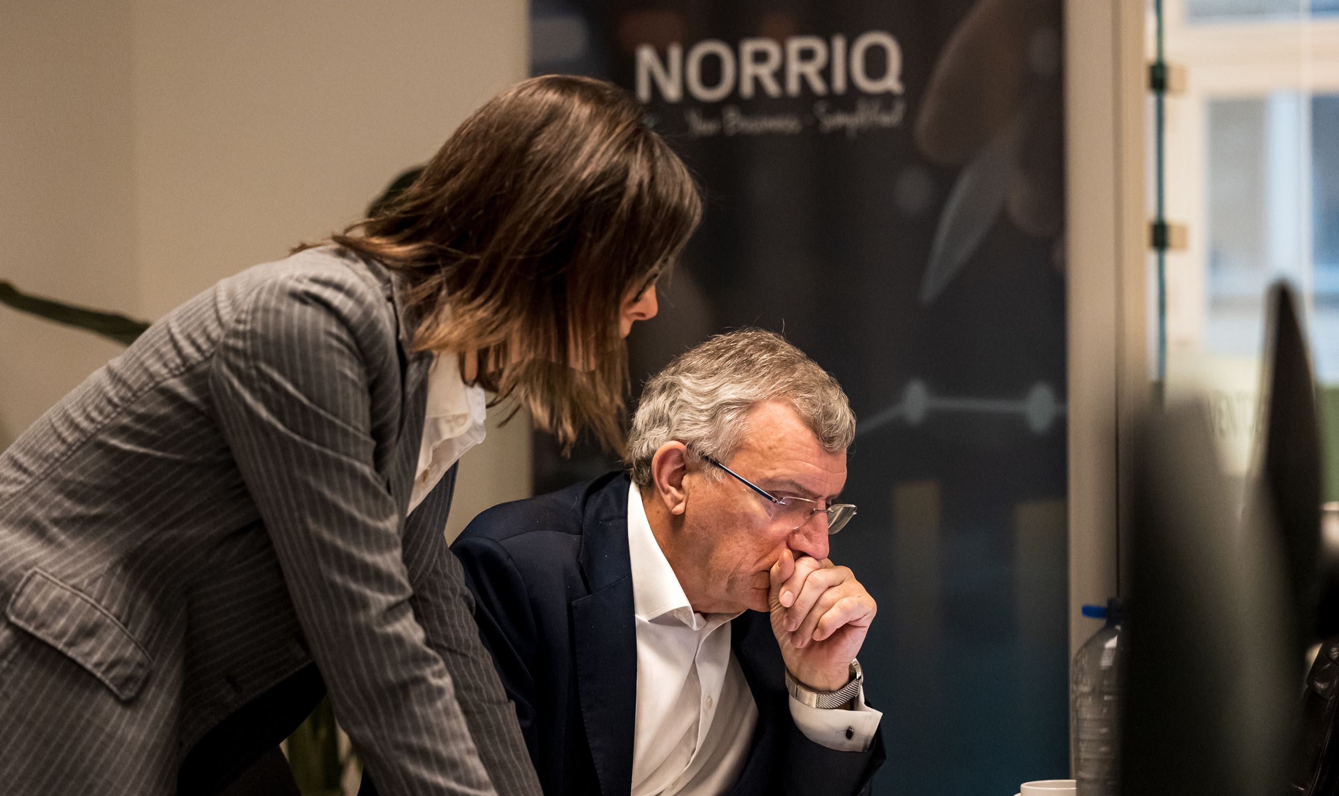 Two colleagues discussing work at a desk in an office environment