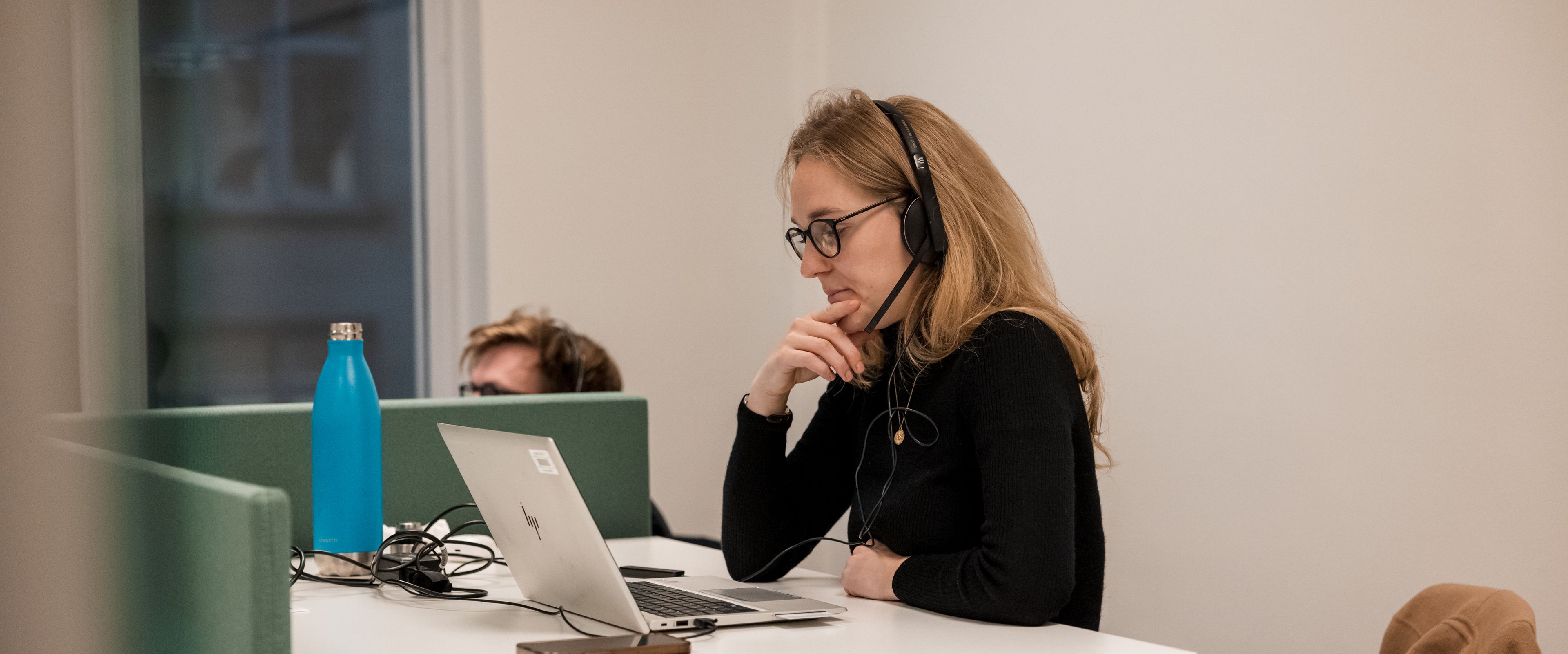 Person with headphones working on a laptop at a desk.